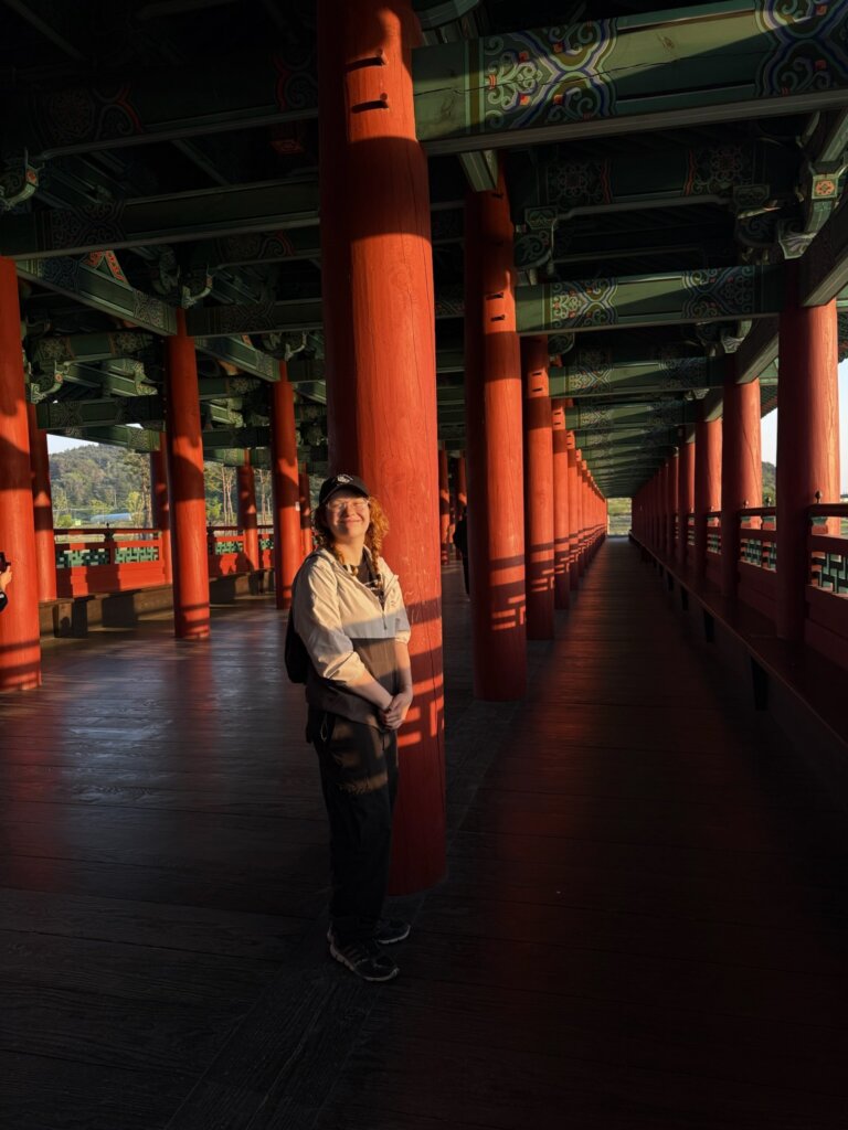 A woman stands in an open structure filled with columns and tinted in red
