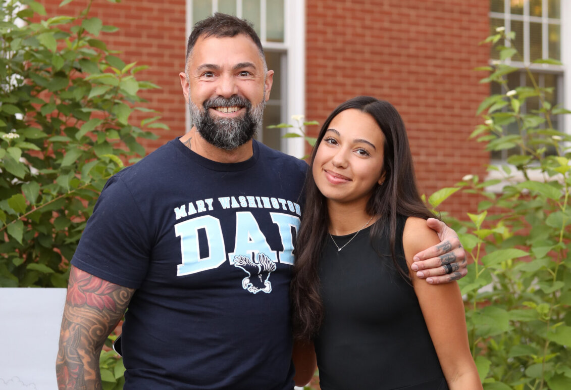 A man wearing a "Mary Washington Dad" T-shirt hugs his daughter