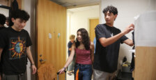 Three people stand inside a college residence hall room
