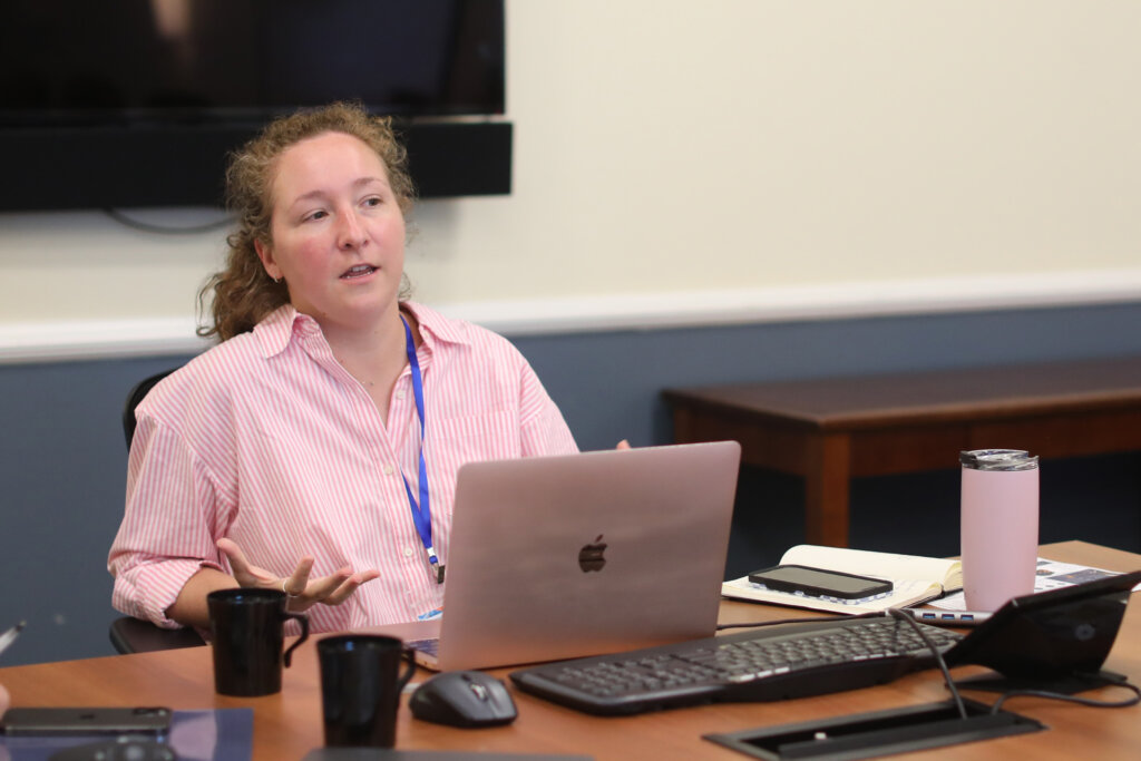 A woman sits behind a laptop