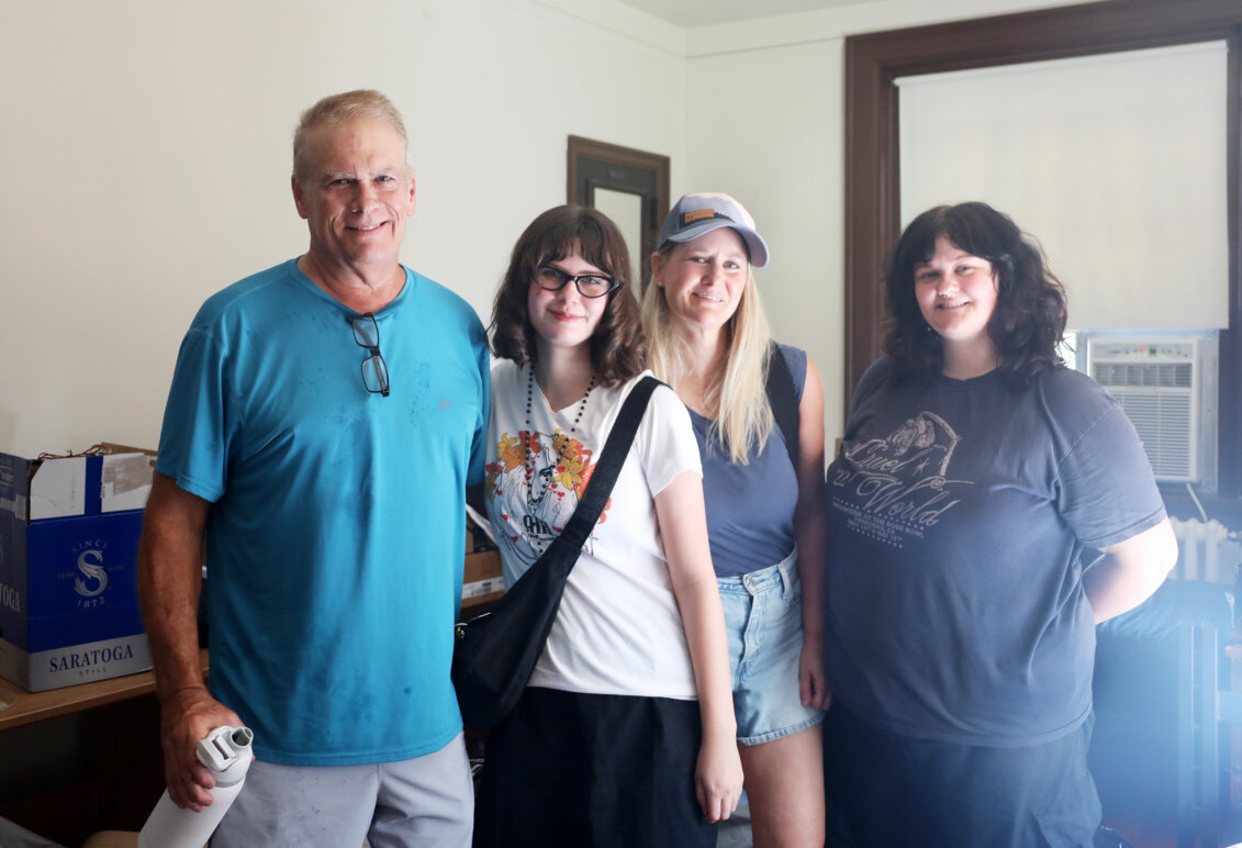A father, mother and two sisters stand posing for the camera inside the doorway of a college residence hall