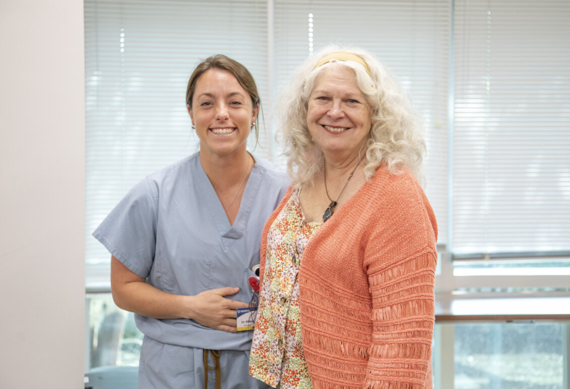 Sabrina Elliott in light blue scrubs smiles next to her former Professor of Biology Deborah O’Dell wearing a peach colored sweater. Photo by K Pearlman Photography.