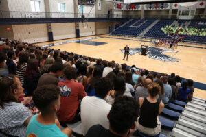 Students in the stands of the Anderson Center and President Paino in the center of the floor giving a Welcome Address