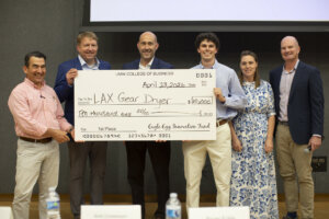 six people hold an oversized check for $10,000