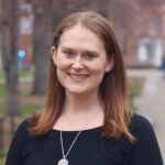 image of woman outdoors on campus with red hair black top