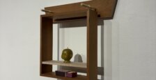 Small wooden wall-mounted shelf displaying a green sculpted head and two small rectangular objects.