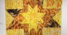 Large yellow and orange textile artwork featuring flame patterns, snack-food imagery and geometric shapes.