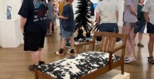 Gallery visitors move among sculptures, furniture and colorful artwork displayed throughout the exhibition space.