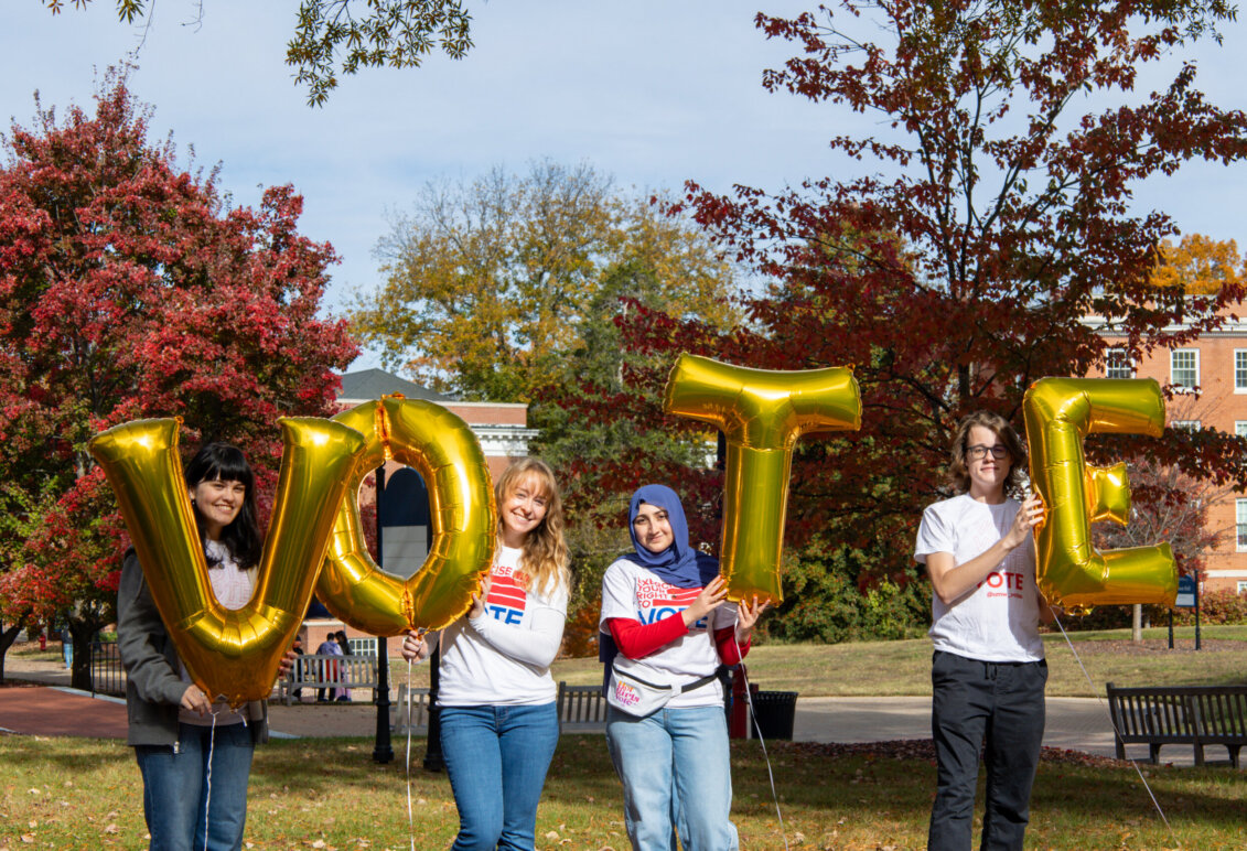 students outdoors on UMW campus hold balloon letters that spell VOTE