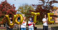 students outdoors on UMW campus hold balloon letters that spell VOTE