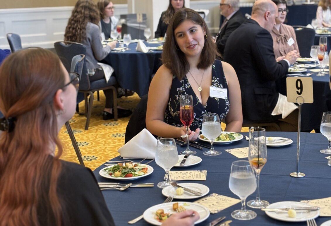 Two students share a conversation over a formal place-setting