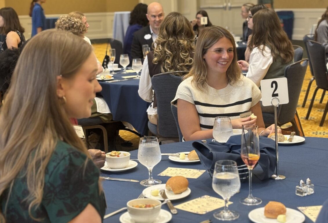 Two students sit at a dining table during an etiquette dinner
