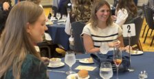 Two students sit at a dining table during an etiquette dinner