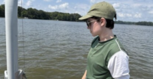 A student stands in a vessel on the water while holding an electronic measuring device