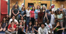 A group of college students pose with younger children inside a school