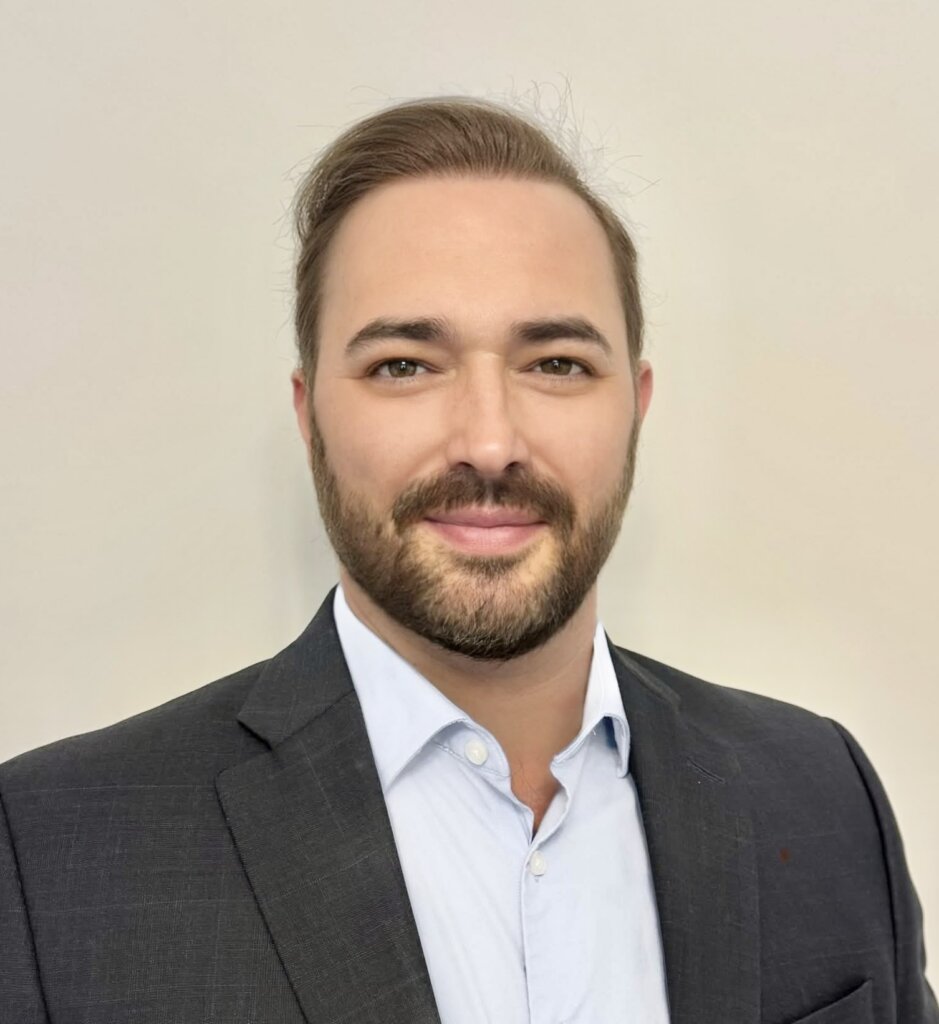 A man wearing a suit jacket smiles for the camera