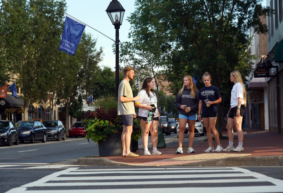 UMW students gather on a sidewalk in downtown Fredericksburg.