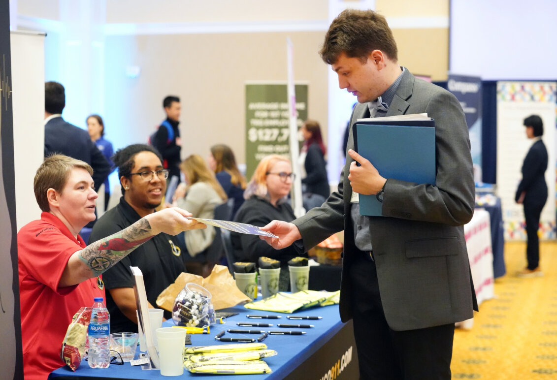 A student takes information from a prospective employer at UMW's Life After Mary Wash Week Career and Internship Fair