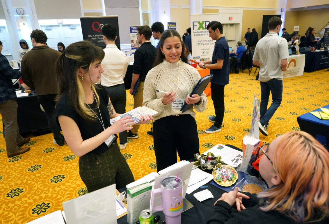 Students approach tables set up at a Career Fair indoors in a building on UMW campus