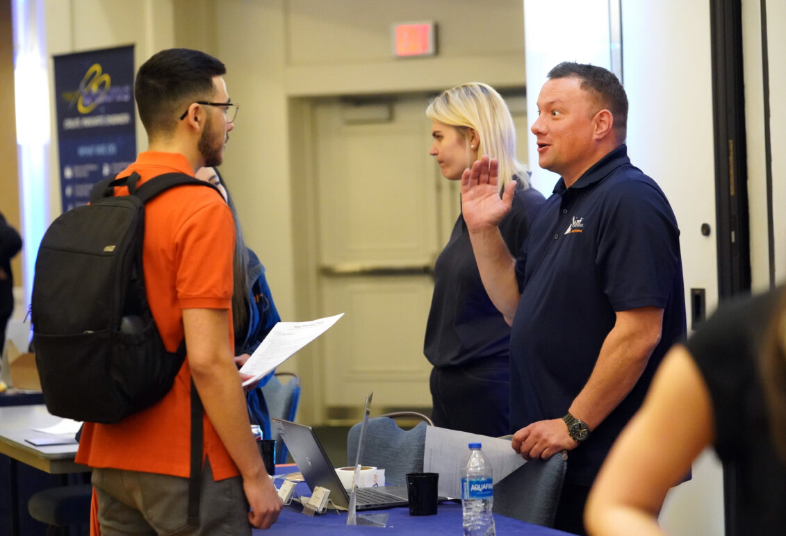 A man speaks with a student at a college career fair