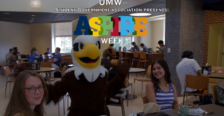 An Eagle mascot stands in a dining room with lots of students in the background, and the words "ASPIRE Week" superimposed on the image