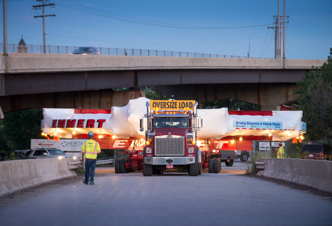 A tractor trailer transporting a giant piece of technology for a physics experiment.