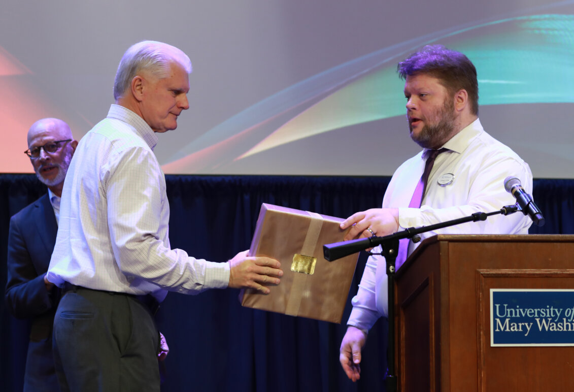 A person accepts an award onstage from another person