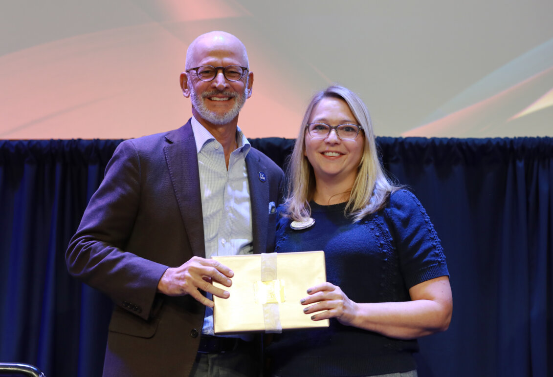 A man and a woman holding an award stand onstage