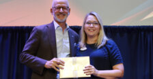A man and a woman holding an award stand onstage