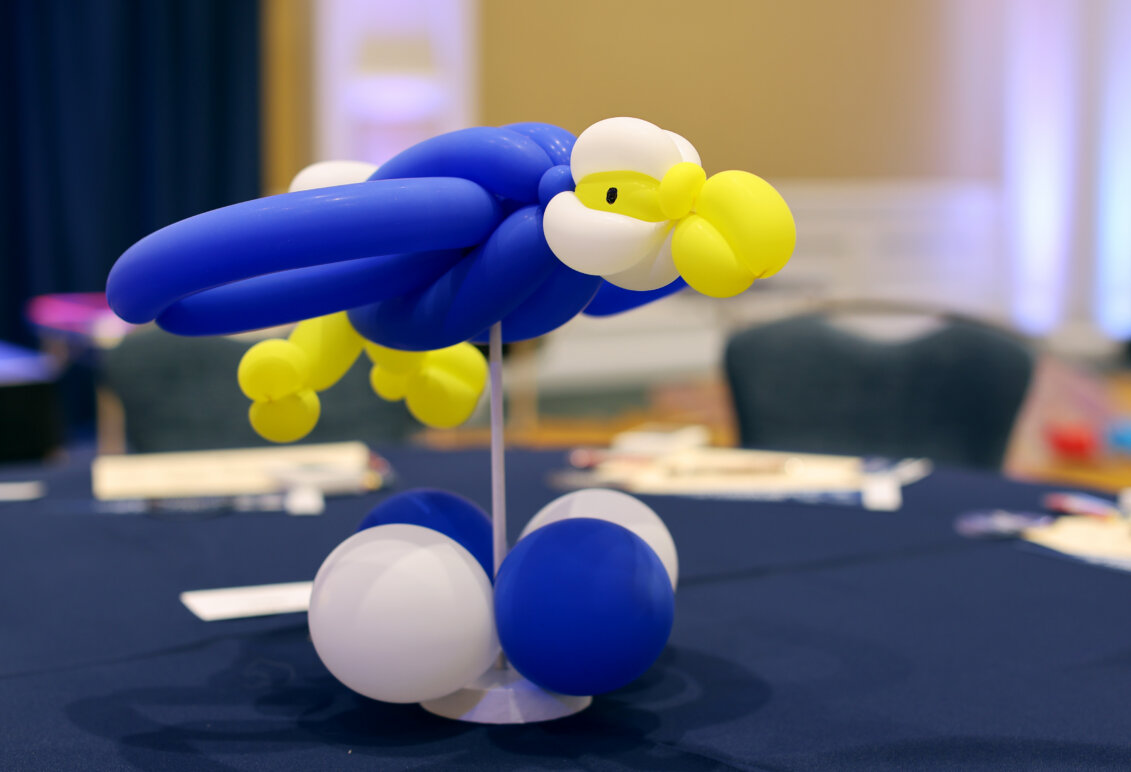 A balloon sculpture in the shape of an Eagle sits in the center of a table