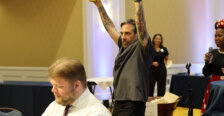 A man stands in the middle of a crowded room holding his hands in the air in a victory pose