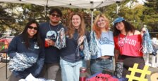 Five students hold spirit sticks behind a table displaying Mary Wash merchandise.