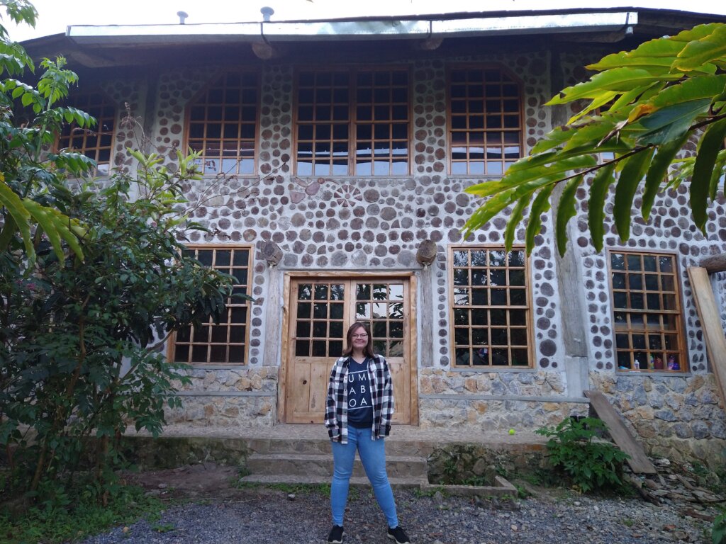 A UMW student in front of a stone building in Guatemala, with tropical trees off to the side.