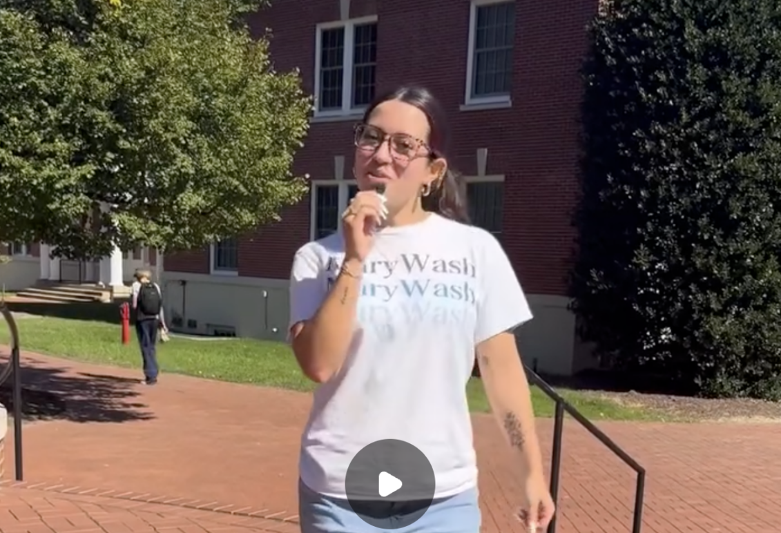 Image of a student in white Mary Wash t-shirt standing on brick walkway on campus preparing to interview others