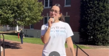 Image of a student in white Mary Wash t-shirt standing on brick walkway on campus preparing to interview others