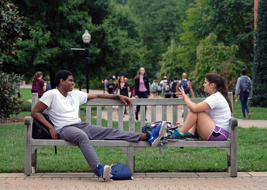 Two students chatting on a bench.