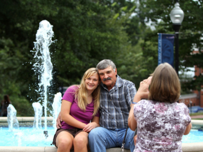 A father and daughter have their photo taken at the fountain.