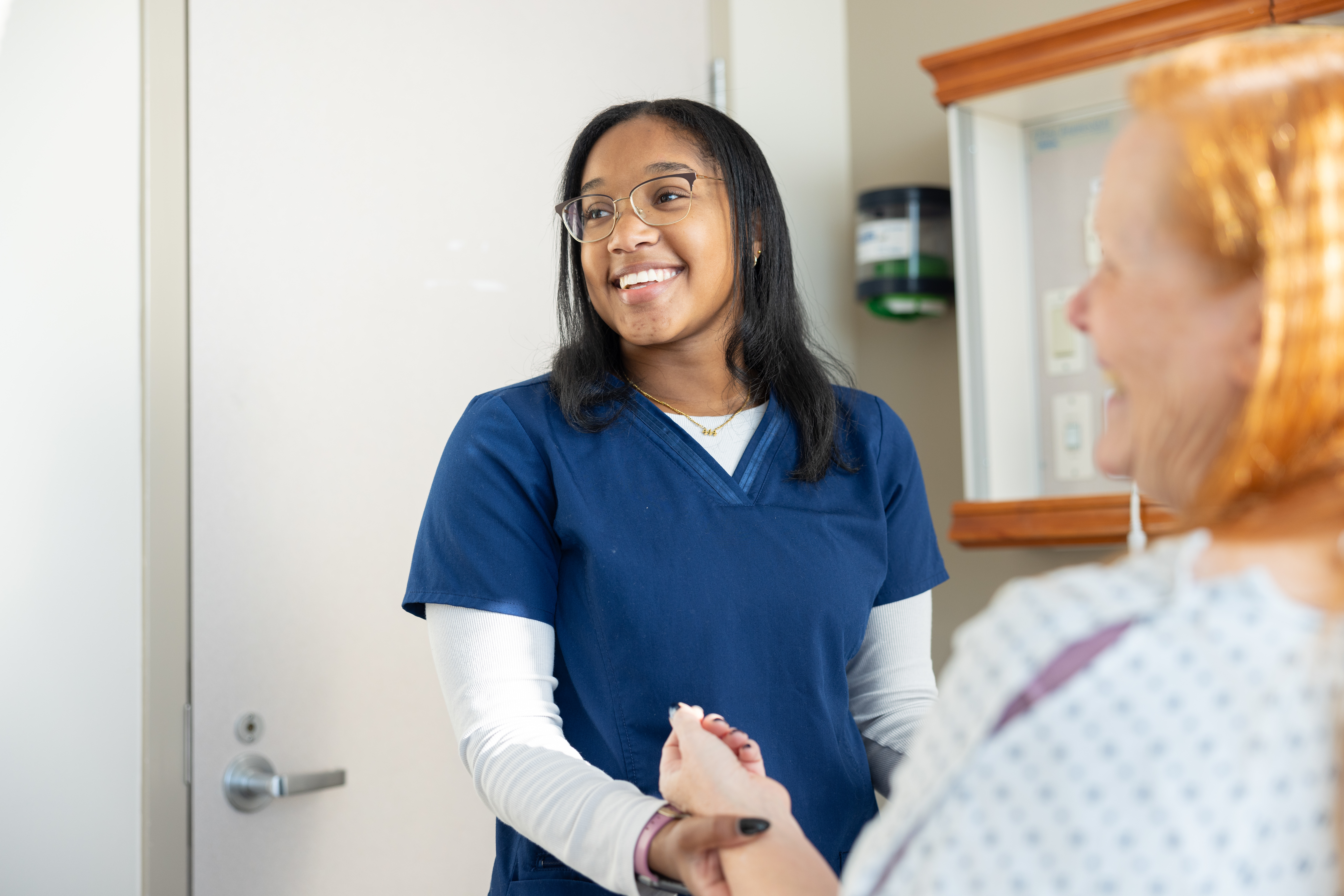 Student and patient smiling in an exam room.