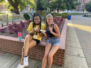 Two campers enjoying ice cream on campus on a hot evening