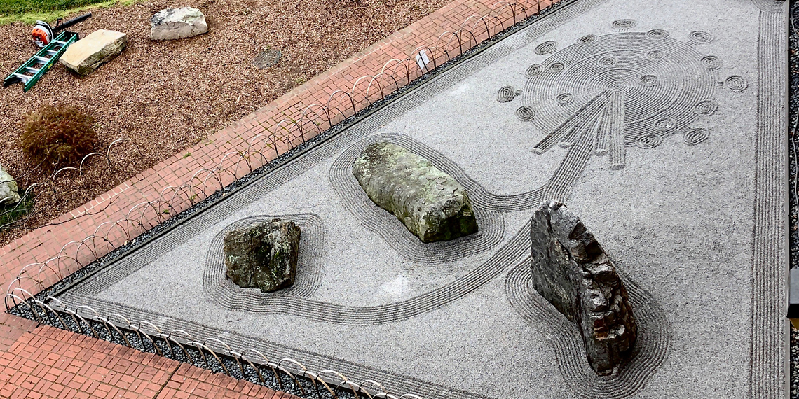 COVID molecule depicted in sand zen garden
