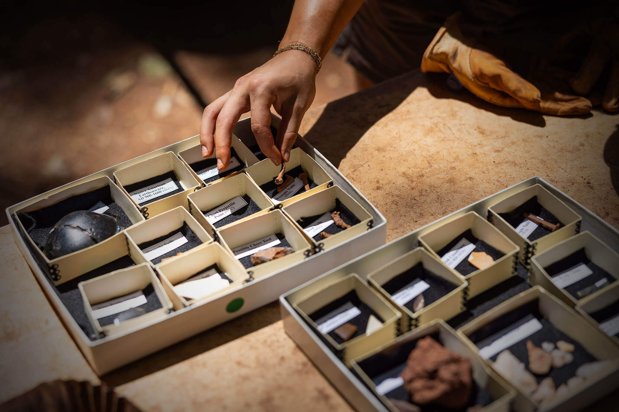 A series of small boxes and a hand setting items into one of those boxes